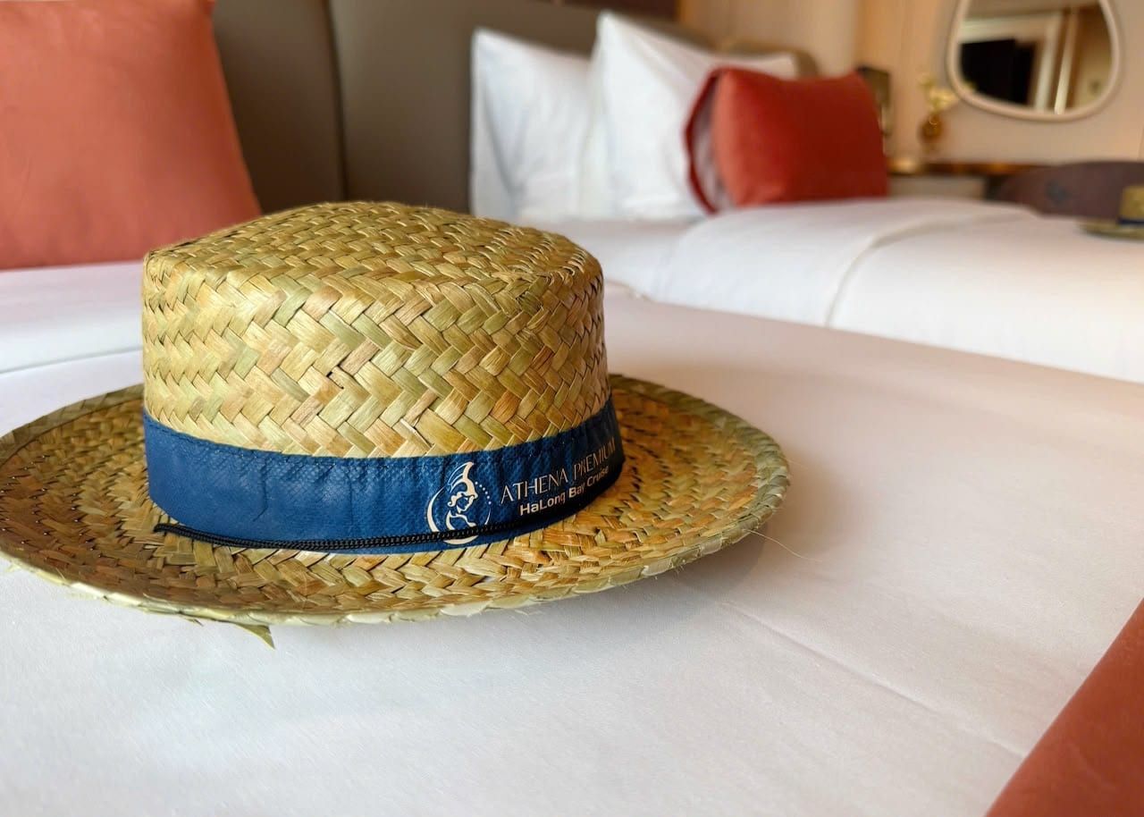 A straw sun hat banded Athena Premium, left on a cabin bed