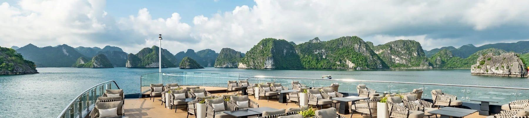 The Azura Cruise sundeck laid with rattan furniture, karsts beyond