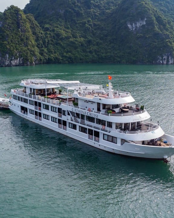 Athena Luxury anchored below a forested karst in Ha Long Bay