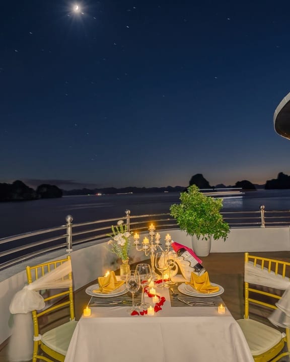A candlelit dinner laid on deck under a full moon over the bay