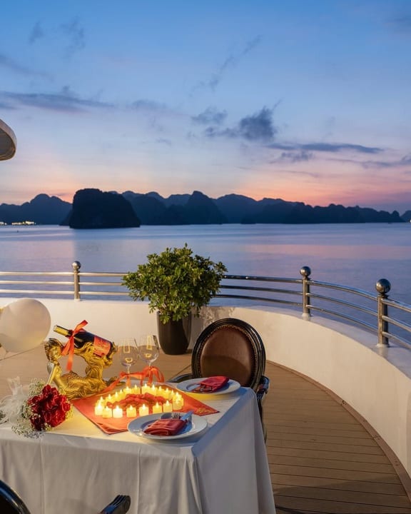 A private dinner laid for two on deck as the sun sets over the bay